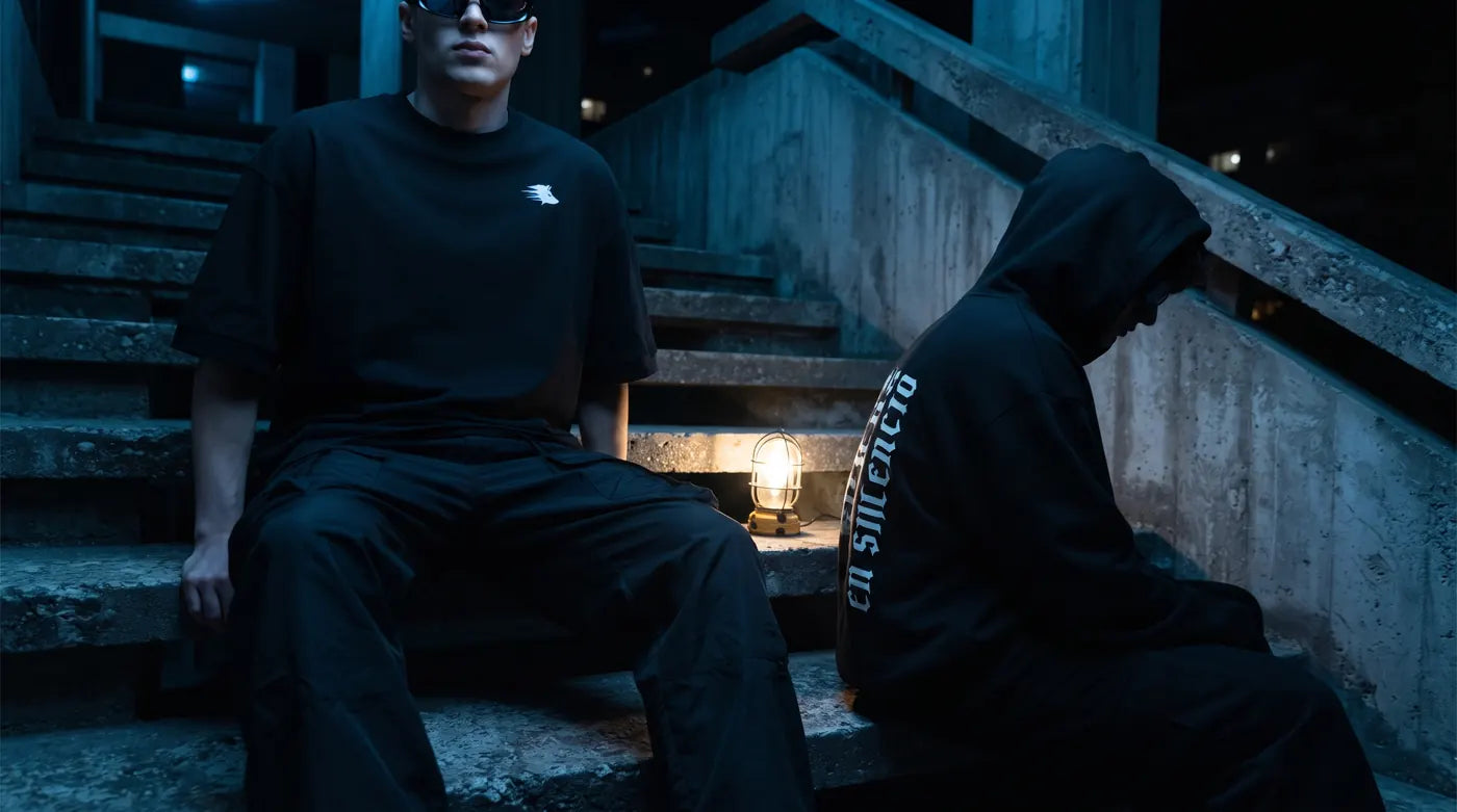 Dos modelos con playera y sudadera WOLVESHOP en escalones de noche
